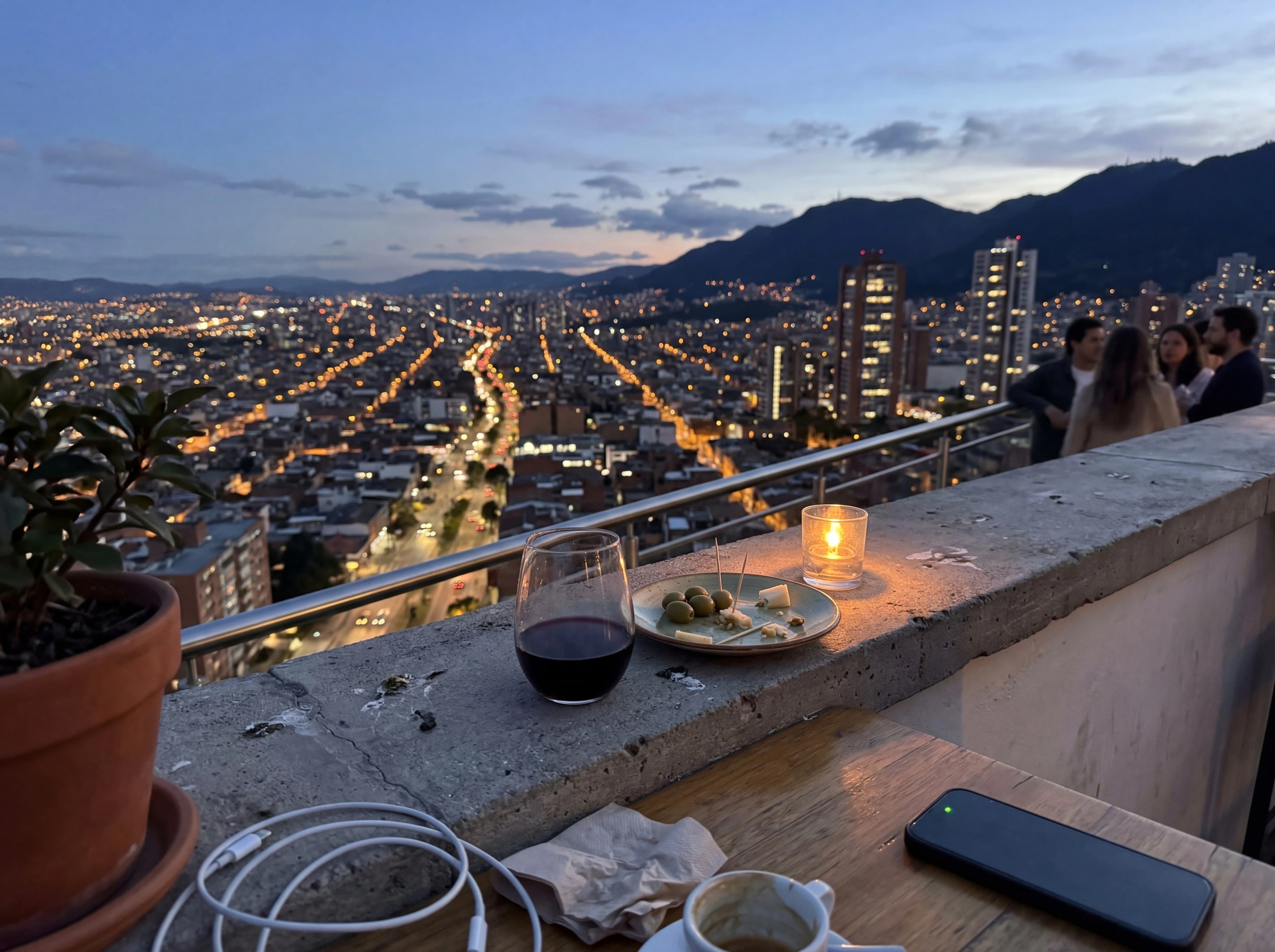 Mountain city skyline at blue hour from a rooftop with wine glass